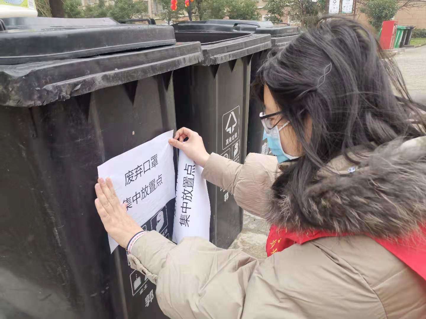 06宁波市北仑区郭巨街道峰南社区计生协志愿者在张贴废弃口罩专用垃圾桶标志.JPG